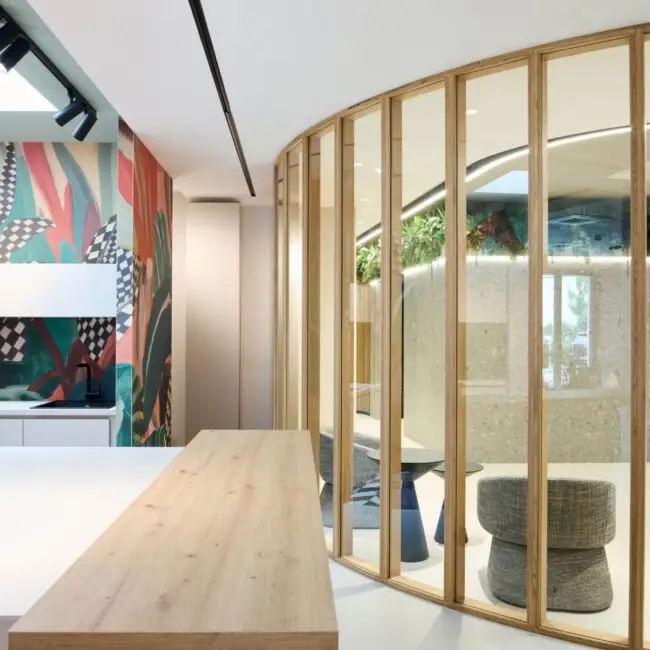Holztheke vor runder Glaswand mit Holzrahmen und bunter Wandgrafik bei Alt & Partner