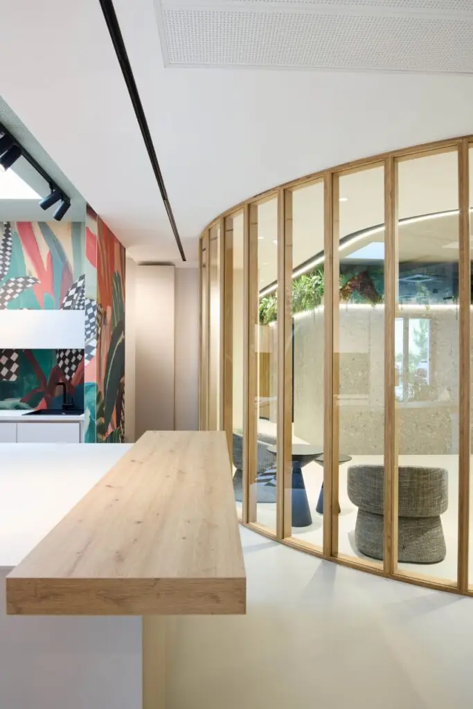 Holztheke vor runder Glaswand mit Holzrahmen und bunter Wandgrafik bei Alt & Partner