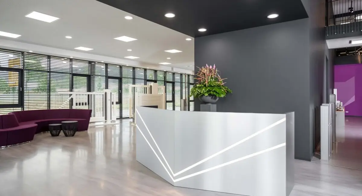 Foyer mit Empfangstresen, violetter Sofalandschaft und Fensterband bei Belfox