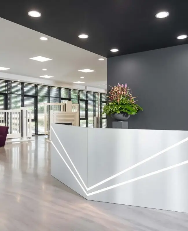 Foyer mit Empfangstresen, violetter Sofalandschaft und Fensterband bei Belfox