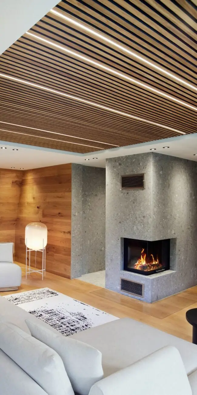 Kamin mit Steinverkleidung, Eichenwand und weißem Sofa in der Private Wellness Suite