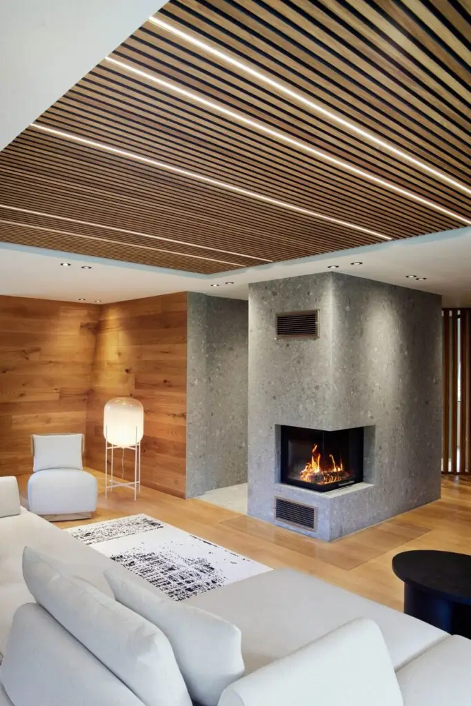 Kamin mit Steinverkleidung, Eichenwand und weißem Sofa in der Private Wellness Suite