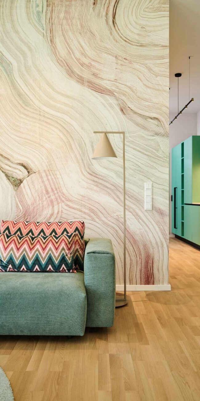 Salbeigrünes Sofa mit Zickzack-Kissen vor Marmor-Wandtapete in der Ferienwohnung