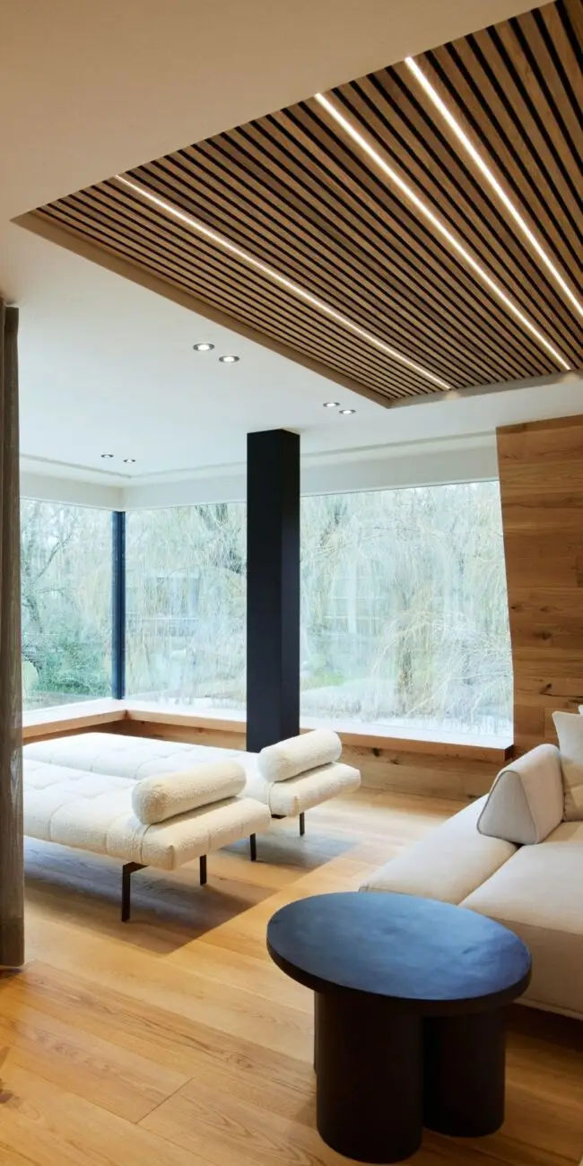 Weiße Liegen und Sofa unter beleuchteter Lamellendecke am Fenster der Private Wellness Suite