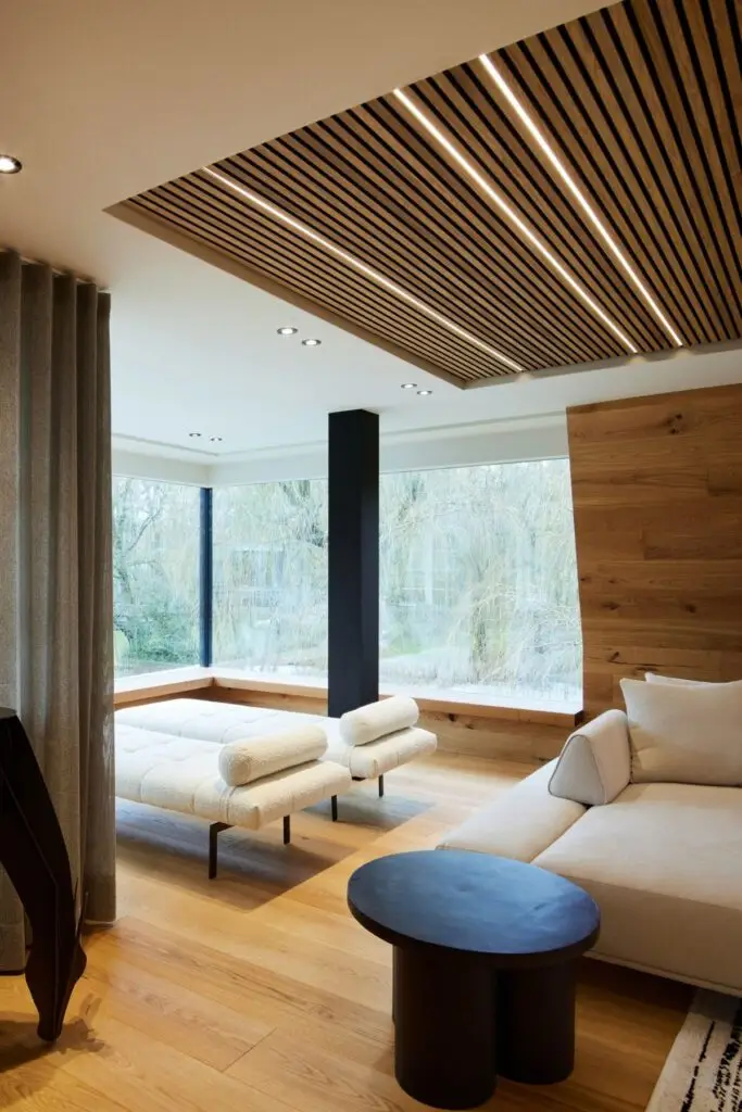 Weiße Liegen und Sofa unter beleuchteter Lamellendecke am Fenster der Private Wellness Suite