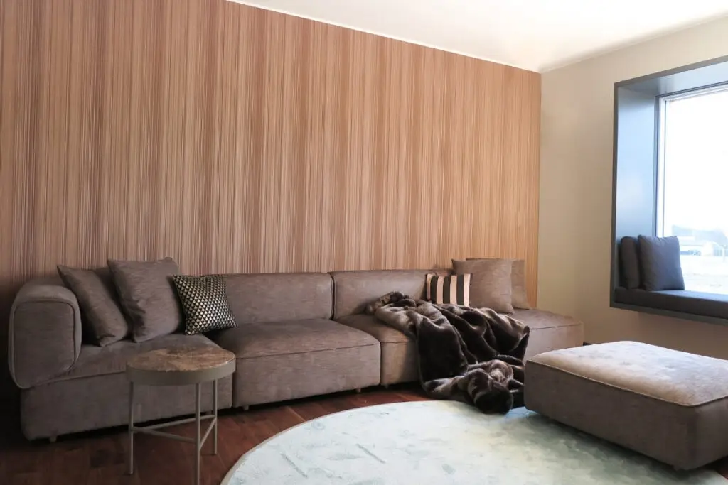 Wohnbereich mit taupefarbenem Ecksofa, Hocker und Streifentapete im Haus S