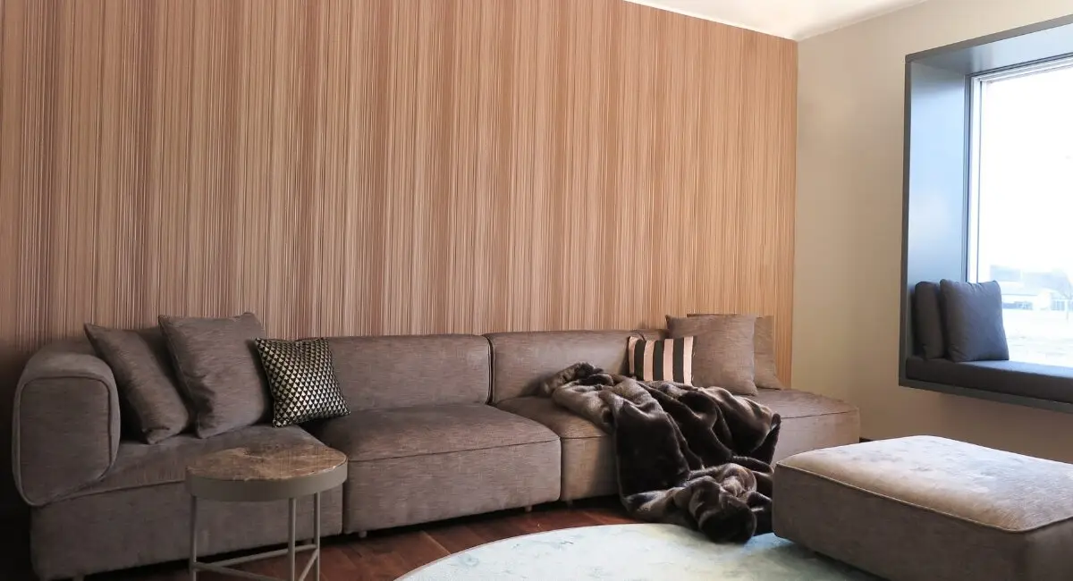 Wohnbereich mit taupefarbenem Ecksofa, Hocker und Streifentapete im Haus S