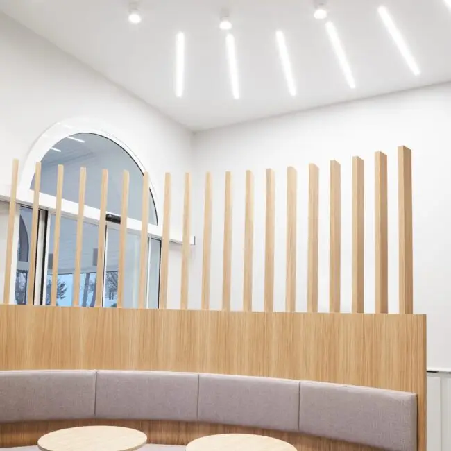 Halbrunde Polsterbank mit Lamellenwand unter linearen Deckenleuchten, Lobby im Haus der Standesbeamten