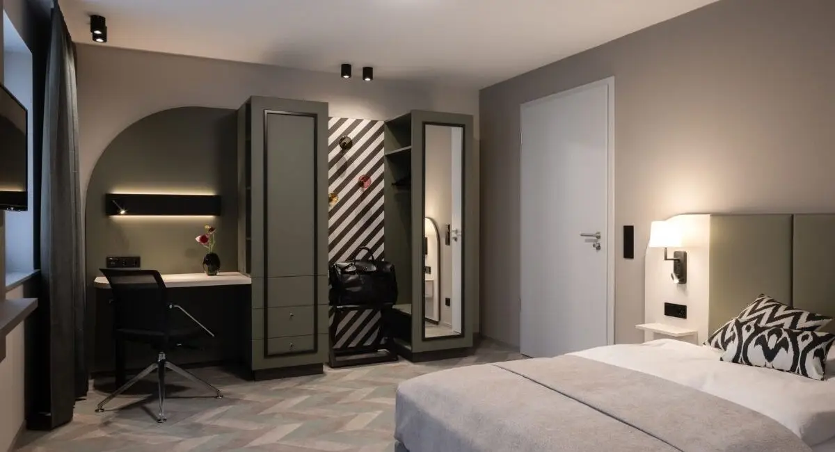 Hotelzimmer mit Doppelbett, Schreibplatz und Garderobe in Grau und Salbei, Haus der Standesbeamten Haus 3