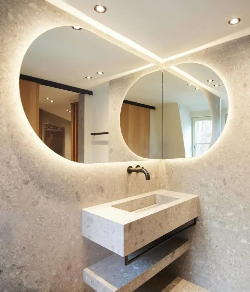 Waschtisch aus Terrazzo mit zwei beleuchteten Rundspiegeln in der Private Wellness Suite