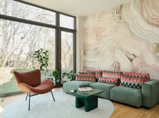 Wohnzimmer mit grünem Sofa, Marmortapete und großer Fensterfront in der Ferienwohnung in Fulda