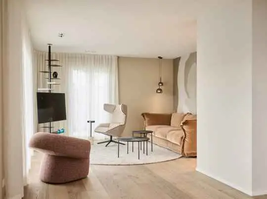 Wohnbereich mit rosa Sessel, Medienwand und hellen Vorhängen im Haus R in Fulda