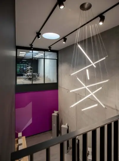 Treppenhaus mit Lichtinstallation, Stahlgeländer und Blick in die magentafarbene Halle bei Belfox