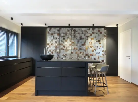 Wohnküche mit schwarzer Kochinsel, Barhockern und Mosaikwand im Haus S in Sommerach